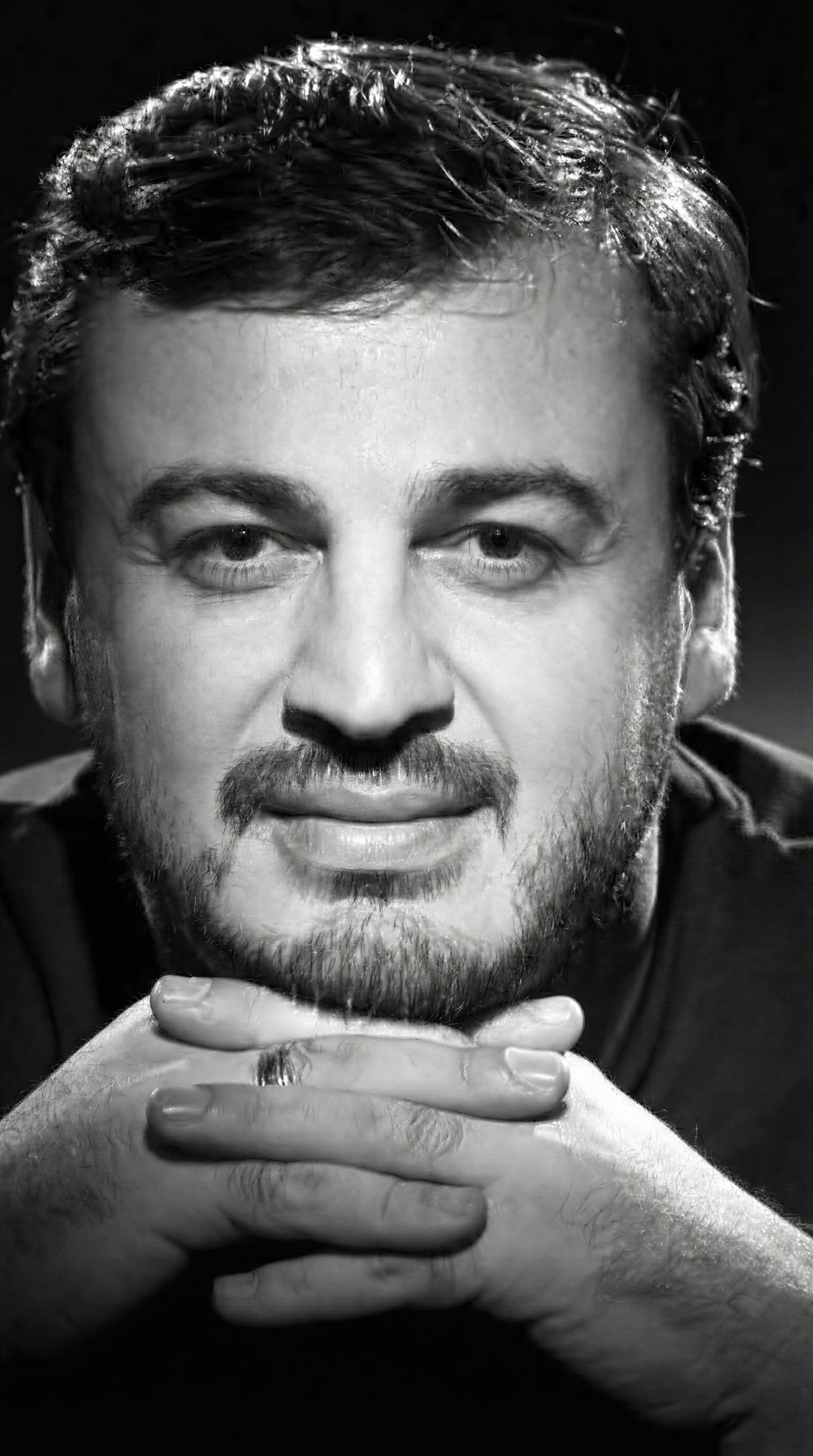 Irakli Kakhidze black and white studio portrait with hands clasped